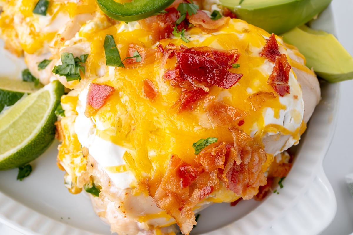 angled close up shot of jalapeno popper chicken topped with cheese and bacon