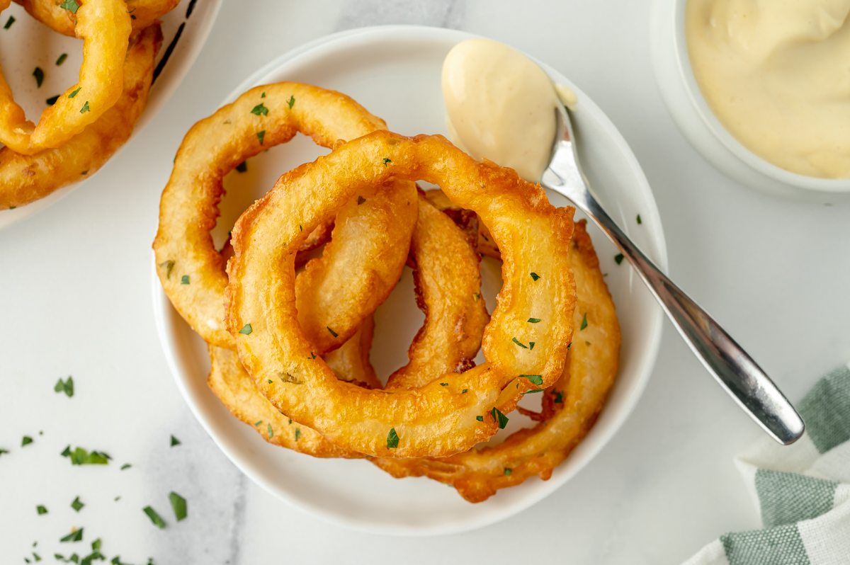 overhead shot of plate of onion rings with spoonful of sauce