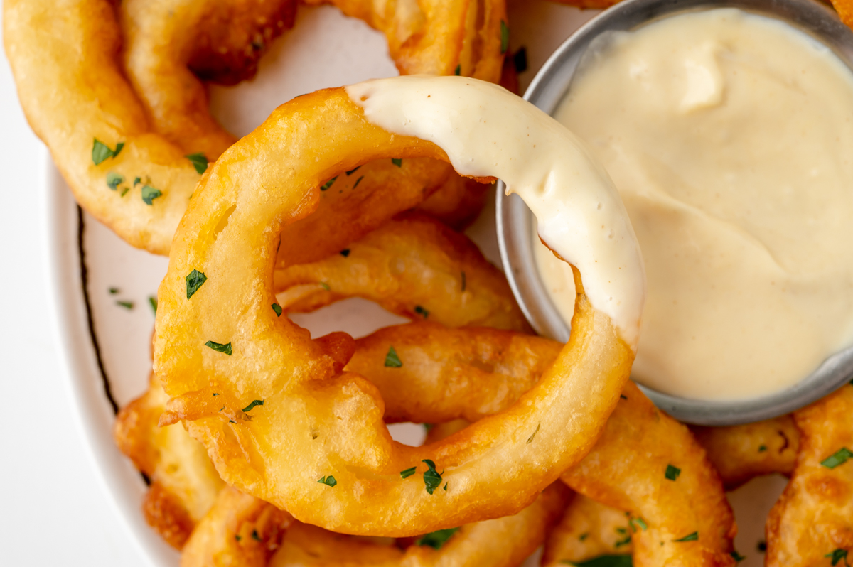 close up of onion ring dipped into sauce