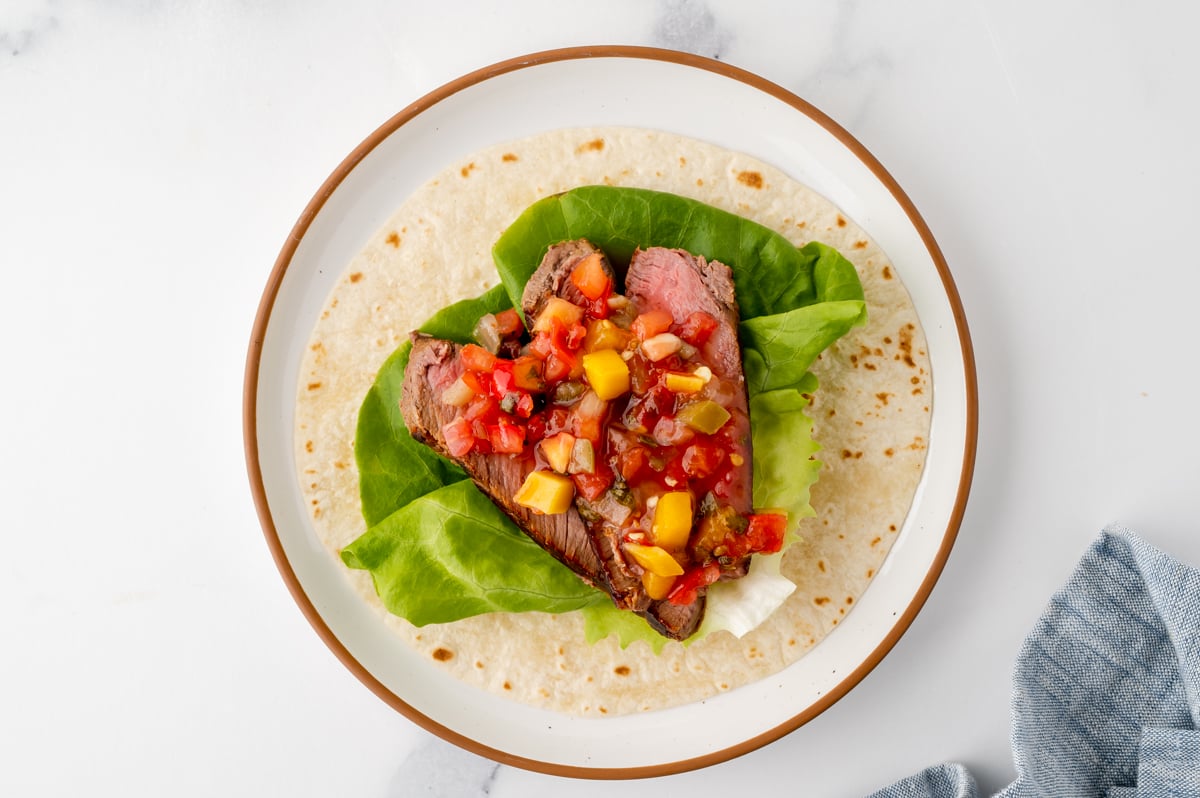 overhead shot of mango salsa over steak on tacos