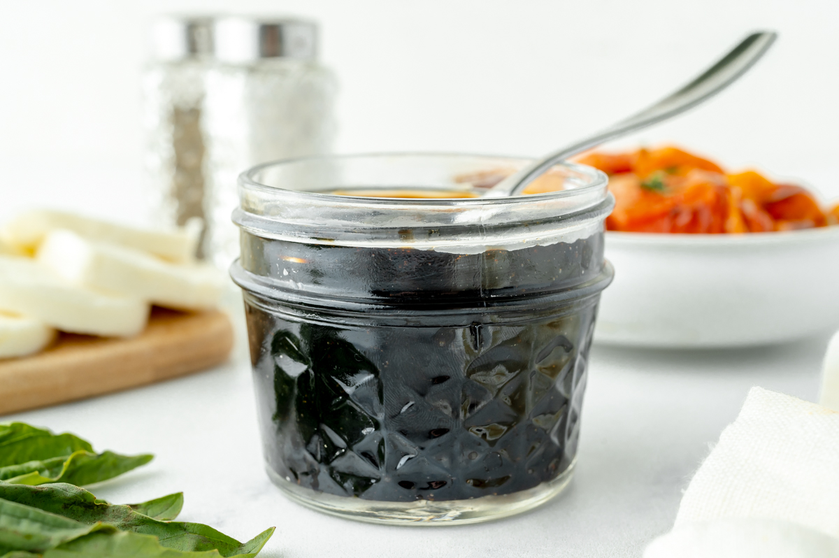 angled shot of spoon in jar of balsamic reduction