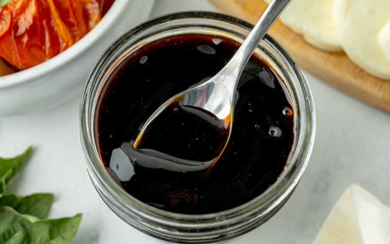 overhead shot of spoon in jar of balsamic glaze