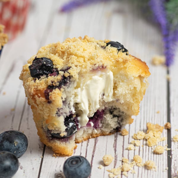 angled shot of bite taken out of blueberry cream cheese muffin