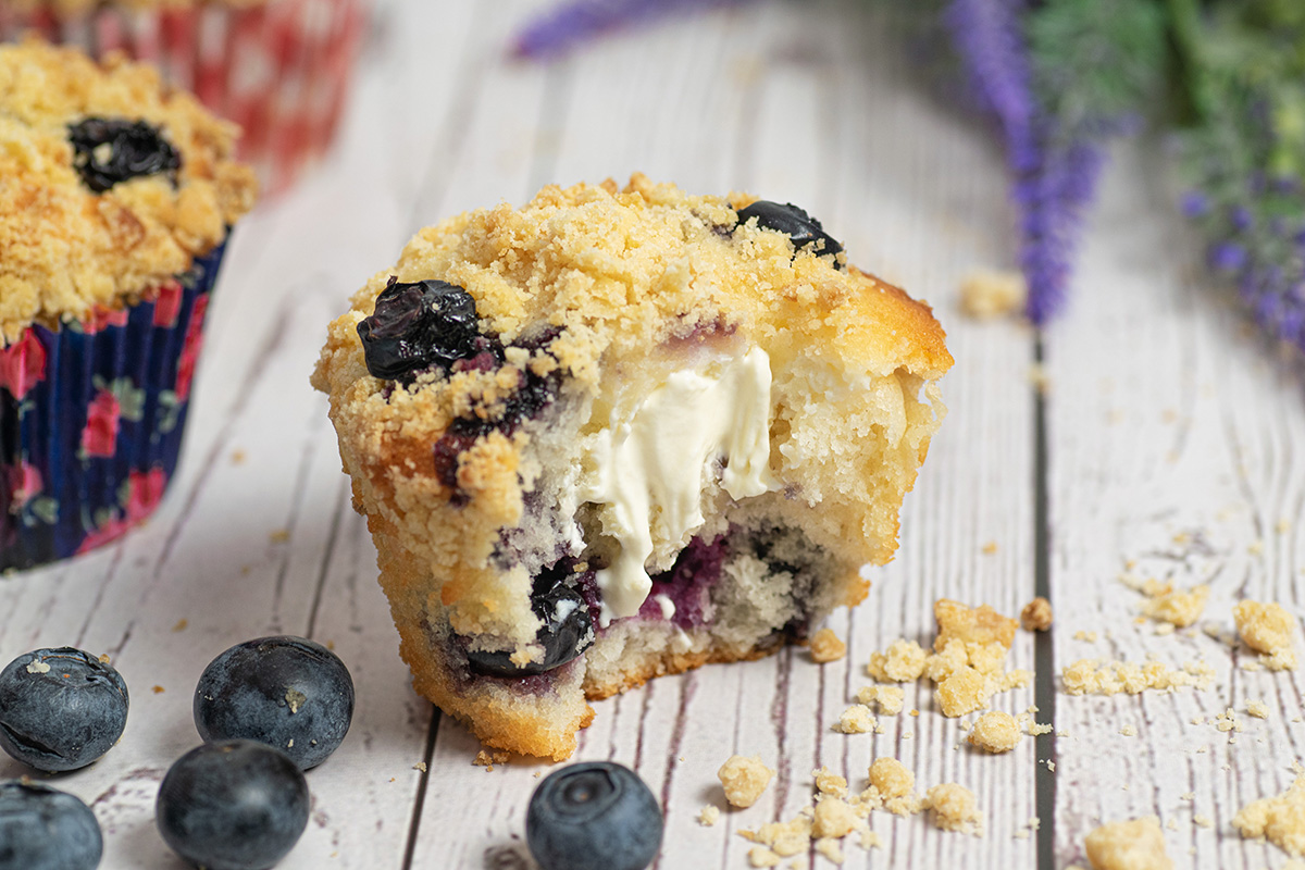 angled shot of bite taken out of blueberry cream cheese muffin