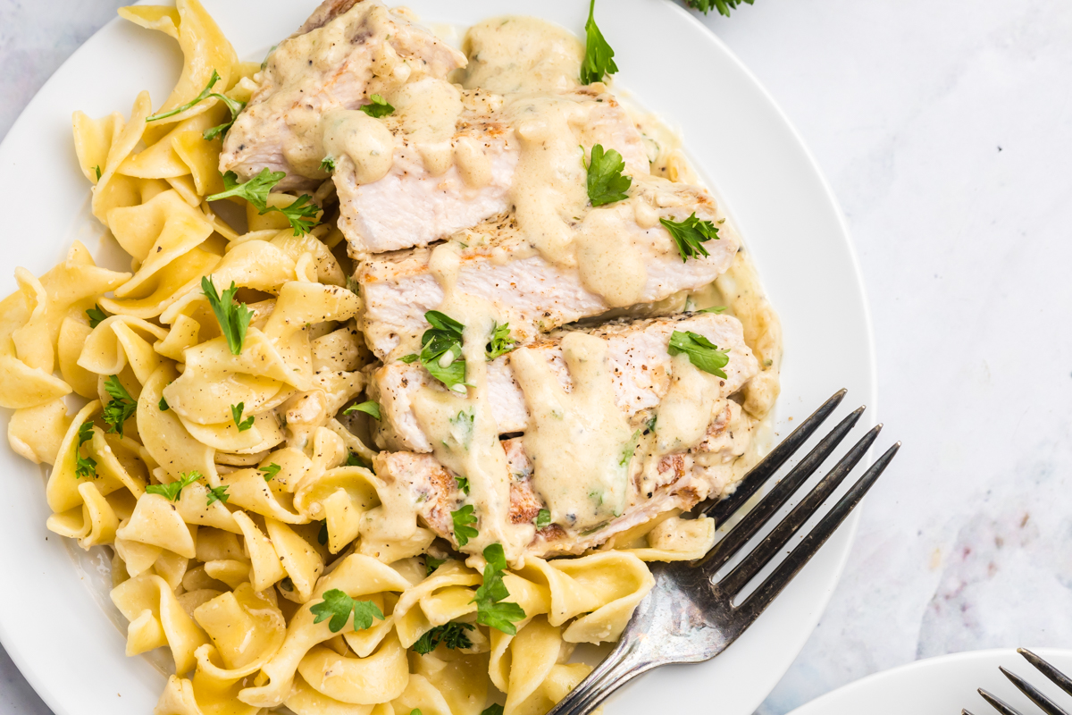 overhead shot of sliced boursin pork pork on plate with noodles