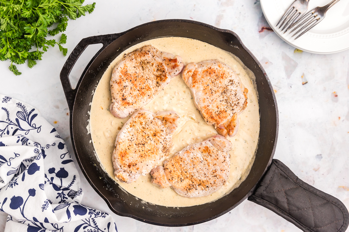 pork chops in creamy sauce in cast iron skillet