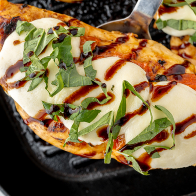 overhead shot of spatula under caprese chicken on grill