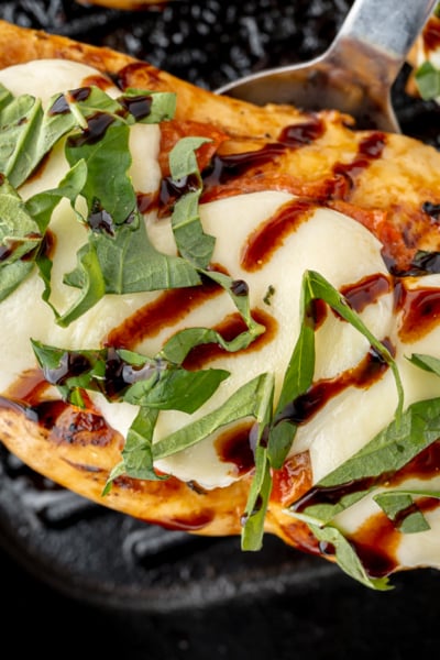 overhead shot of spatula under caprese chicken on grill