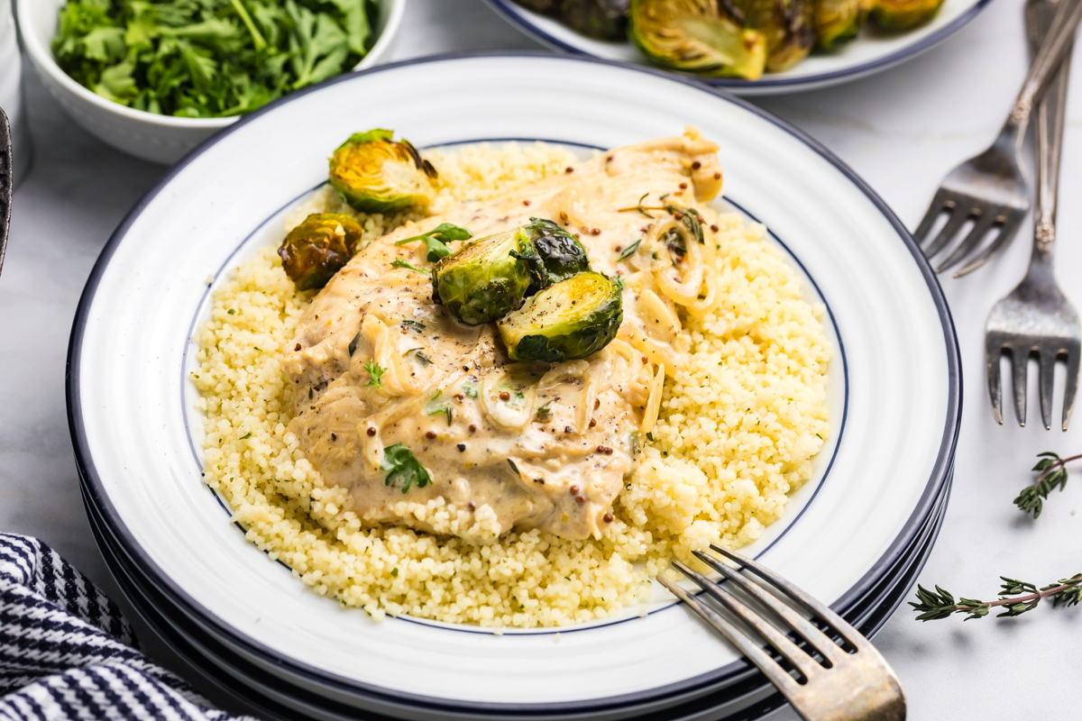 angled shot of creamy dijon chicken over couscous on plate