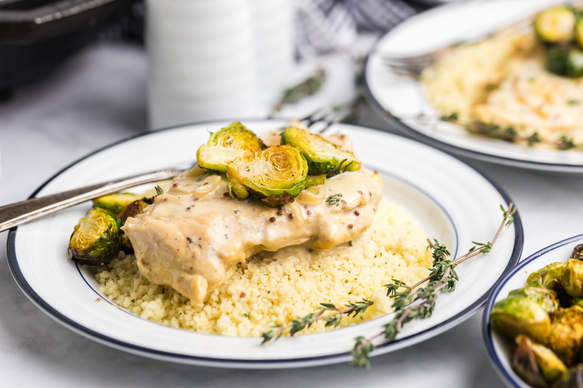 angled shot of brussels sprouts, creamy chicken and couscous on plate