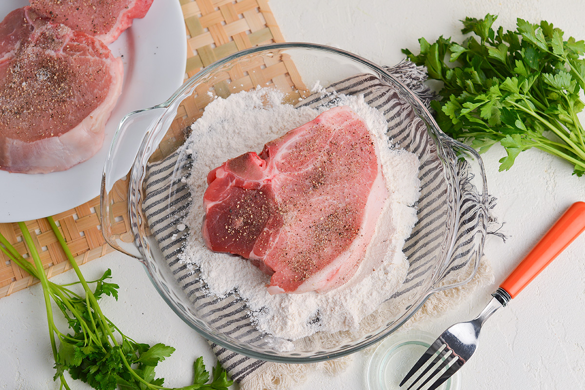 pork chop in bowl of flour