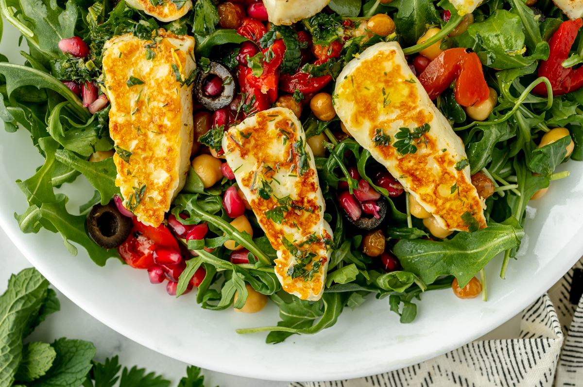 close up overhead shot of 3 pieces of halloumi on salad