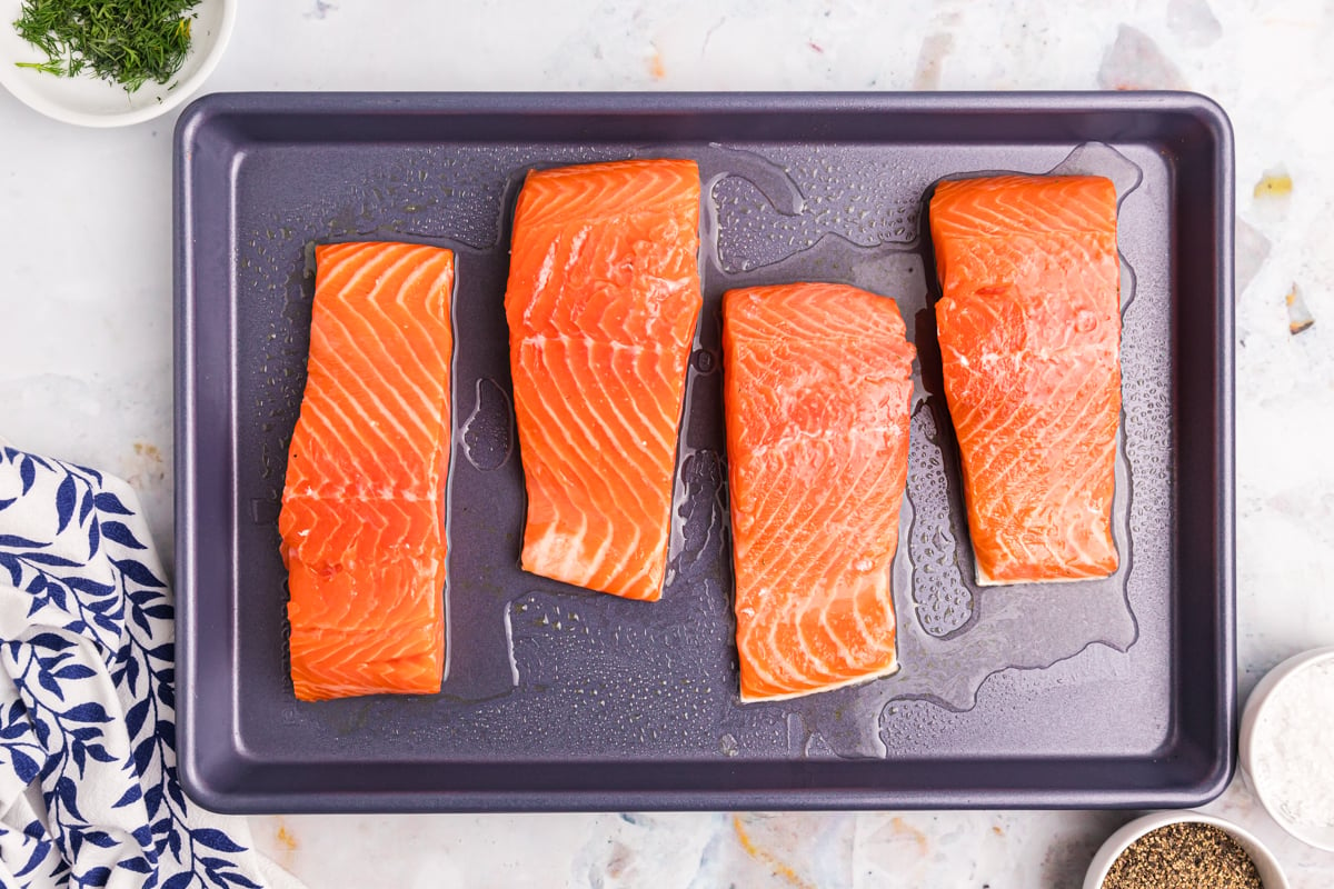 overhead shot of four salmon filets on baking sheet