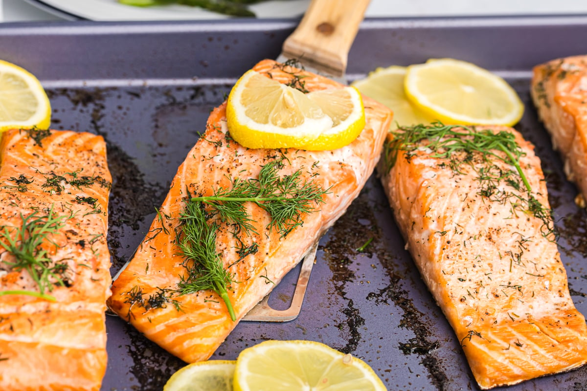 angled shot of spatula lifting lemon dill salmon from baking sheet