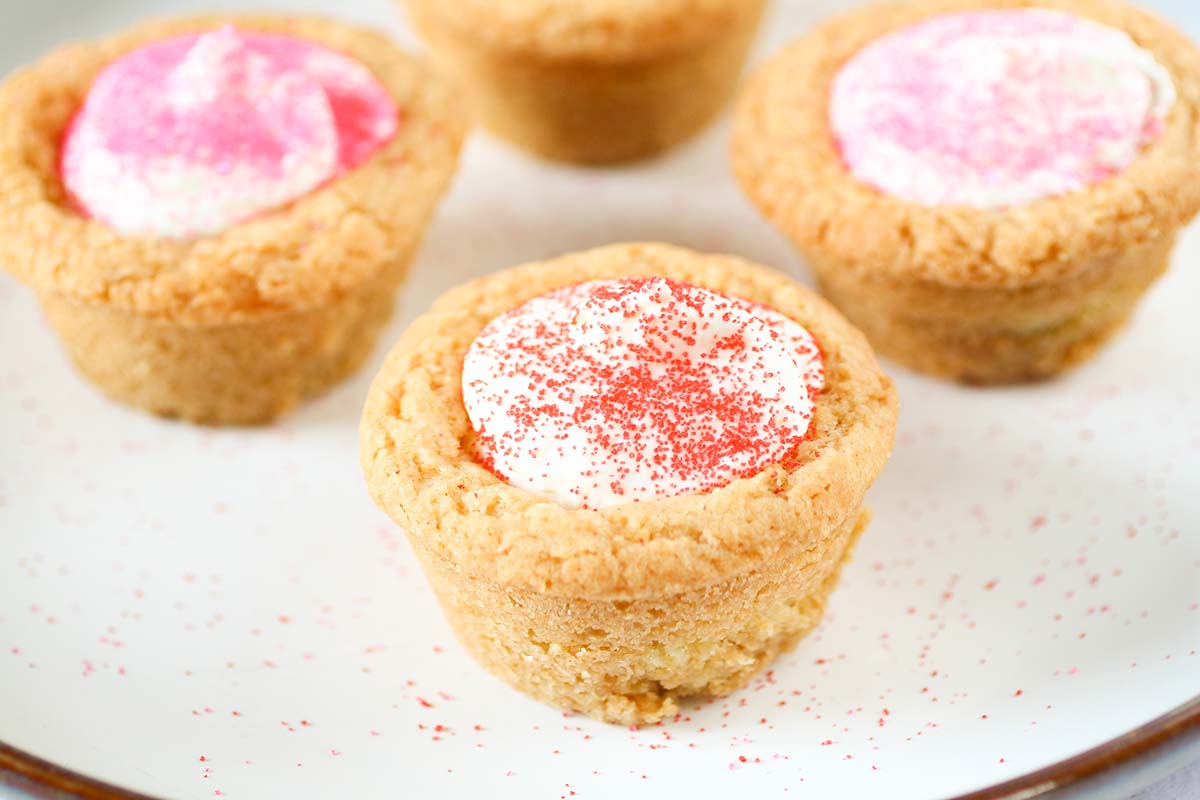 angled shot of raspberry cheesecake cookie cups on white plate