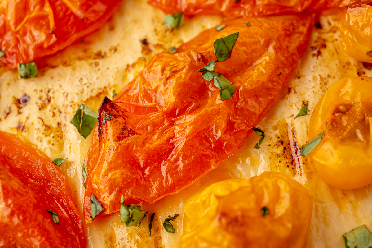 close up overhead shot of roasted tomato topped with basil