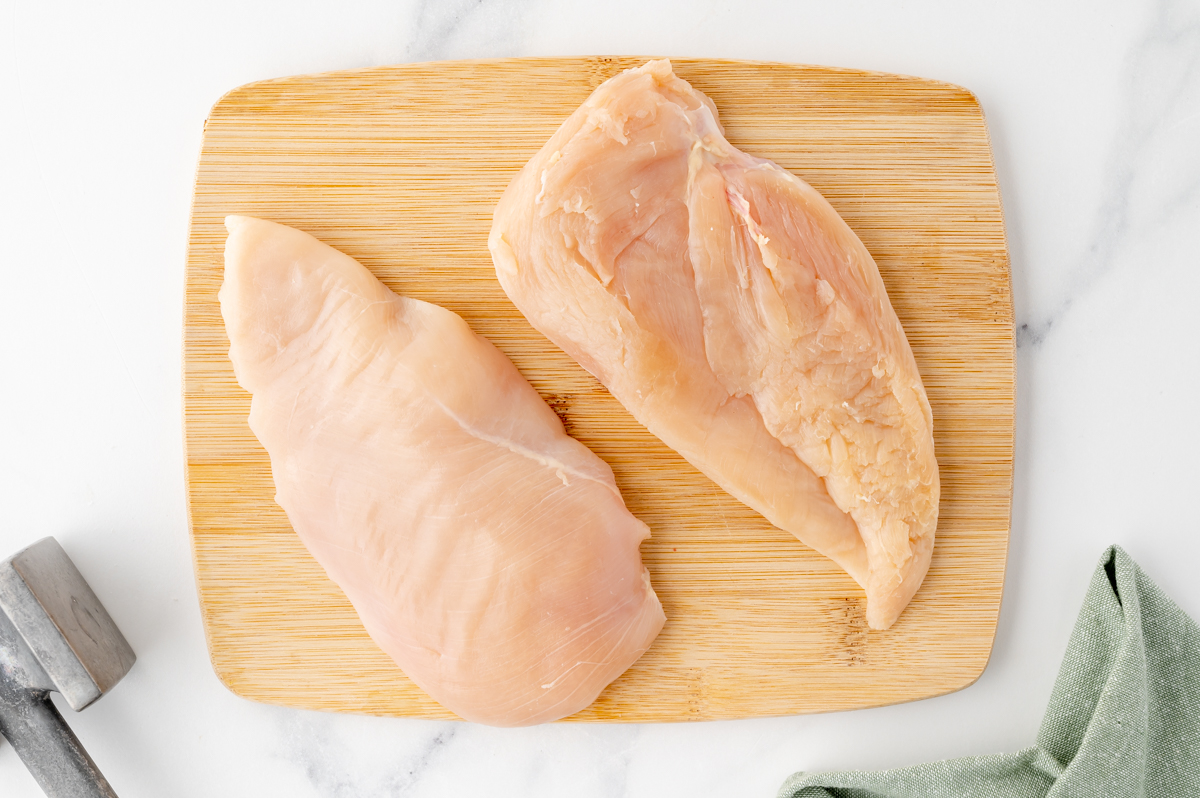 two raw chicken breasts on cutting board