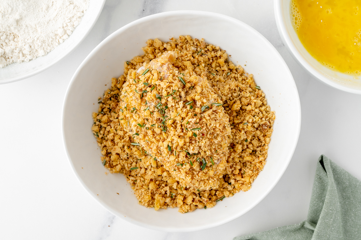 chicken breast in bowl of walnut breading