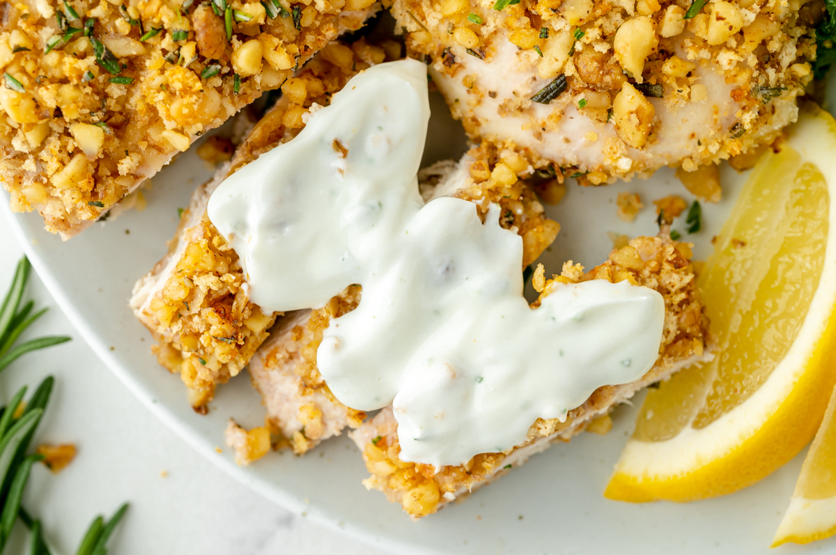 close up overhead shot of creamy sauce over bites of walnut crusted chicken