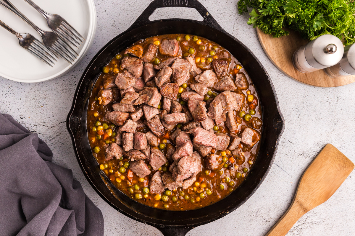 overhead shot of steak bites in skillet of pot pie filling