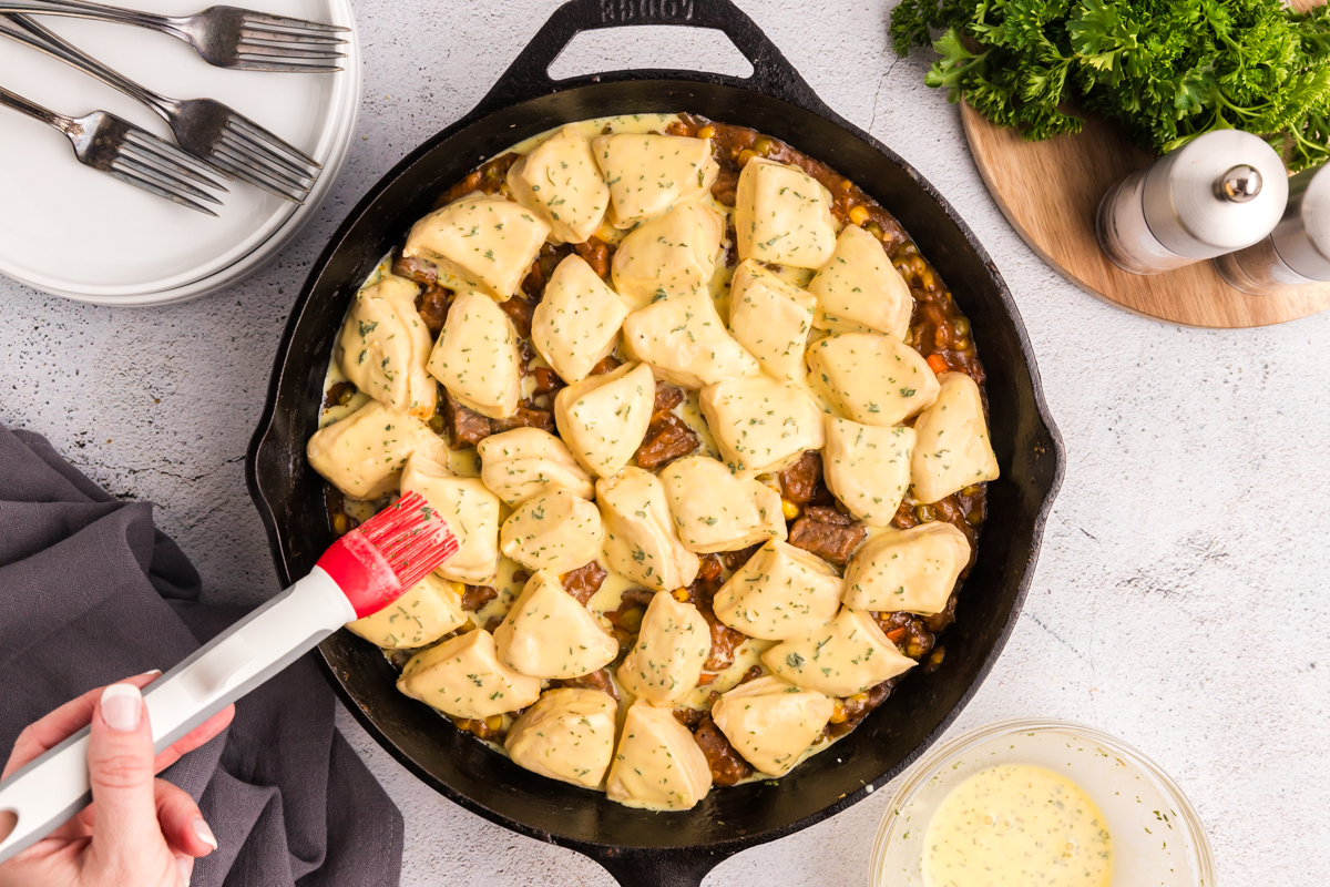 overhead shot of garlic butter brushed on to dough pieces in skillet