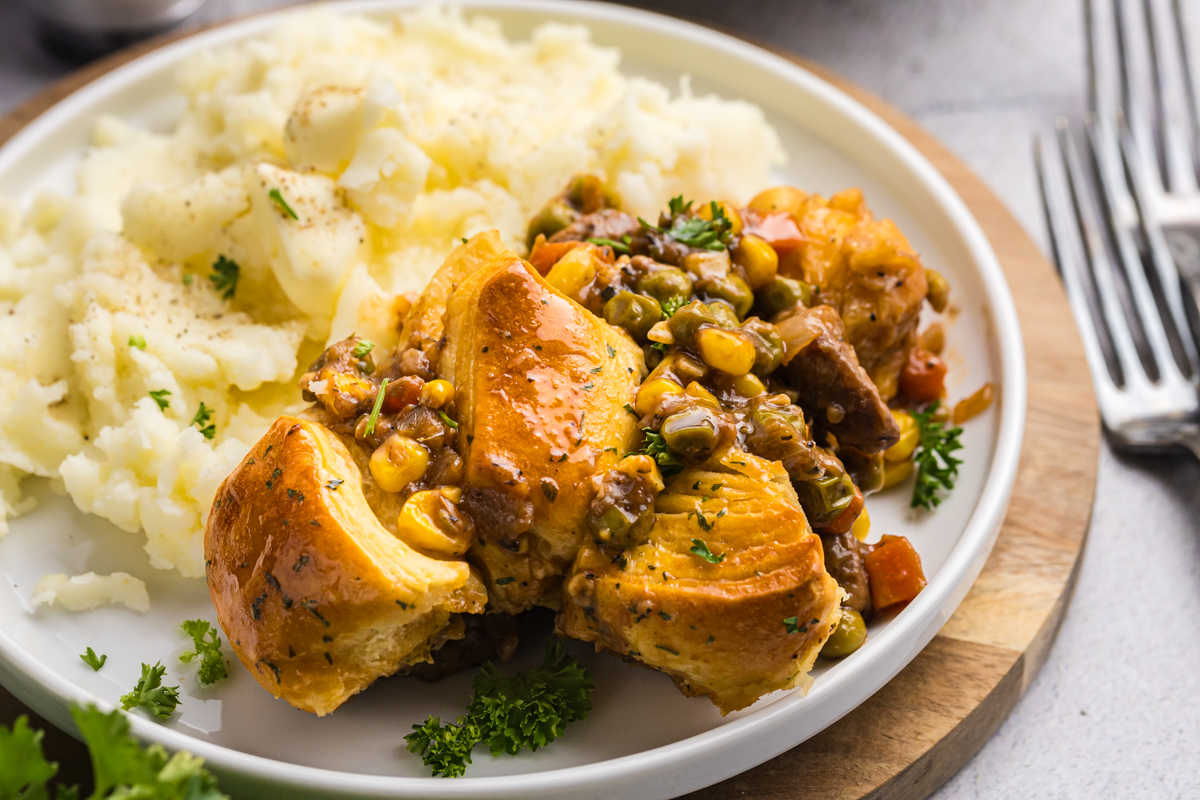 angled shot of beef pot pie on plate with mashed potatoes