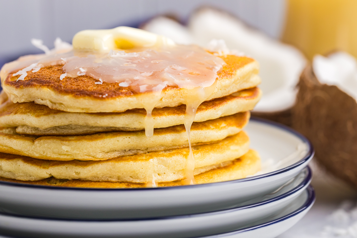 close up straight on shot of syrup dripping off of stack of pancakes