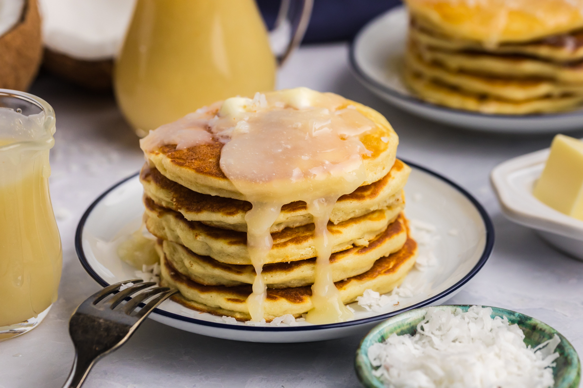 angled shot of syrup dripping off of stack of pancakes