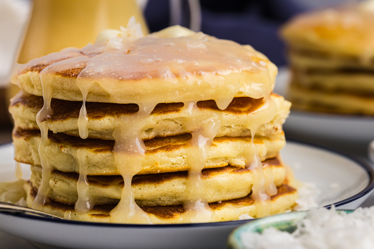 straight on shot of syrup dripping off of stack of coconut pancakes