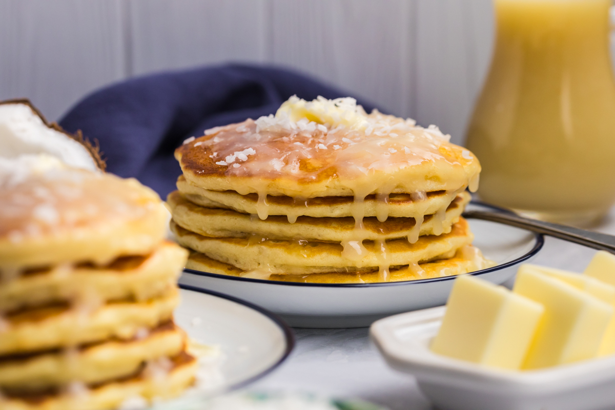 straight on shot of stack of coconut pancakes topped with syrup