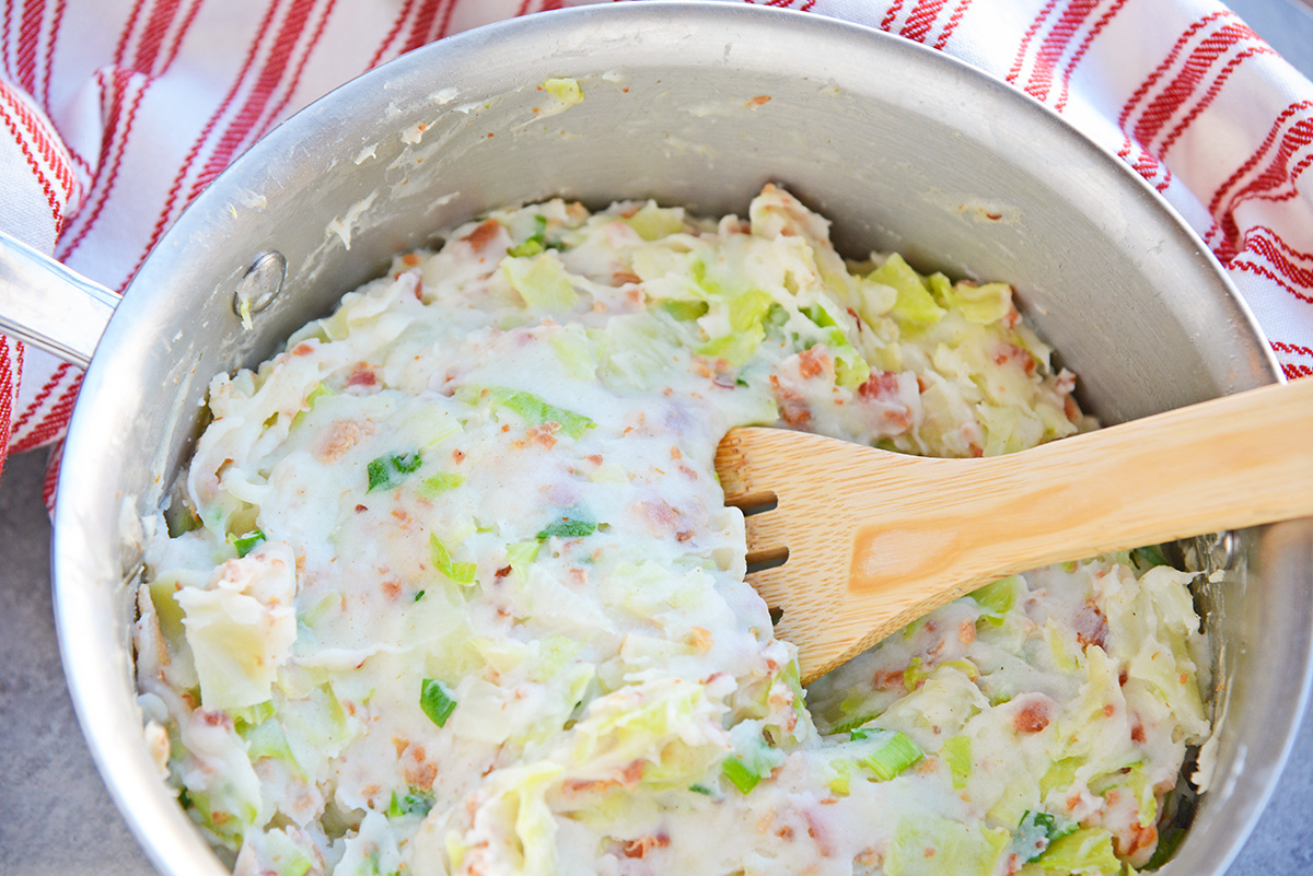 angled shot of colcannon in a saucepan with wooden spoon