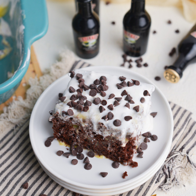 angled shot of slice of irish cream poke cake on stack of plates