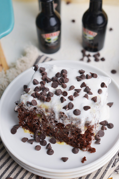 angled shot of slice of irish cream poke cake on stack of plates