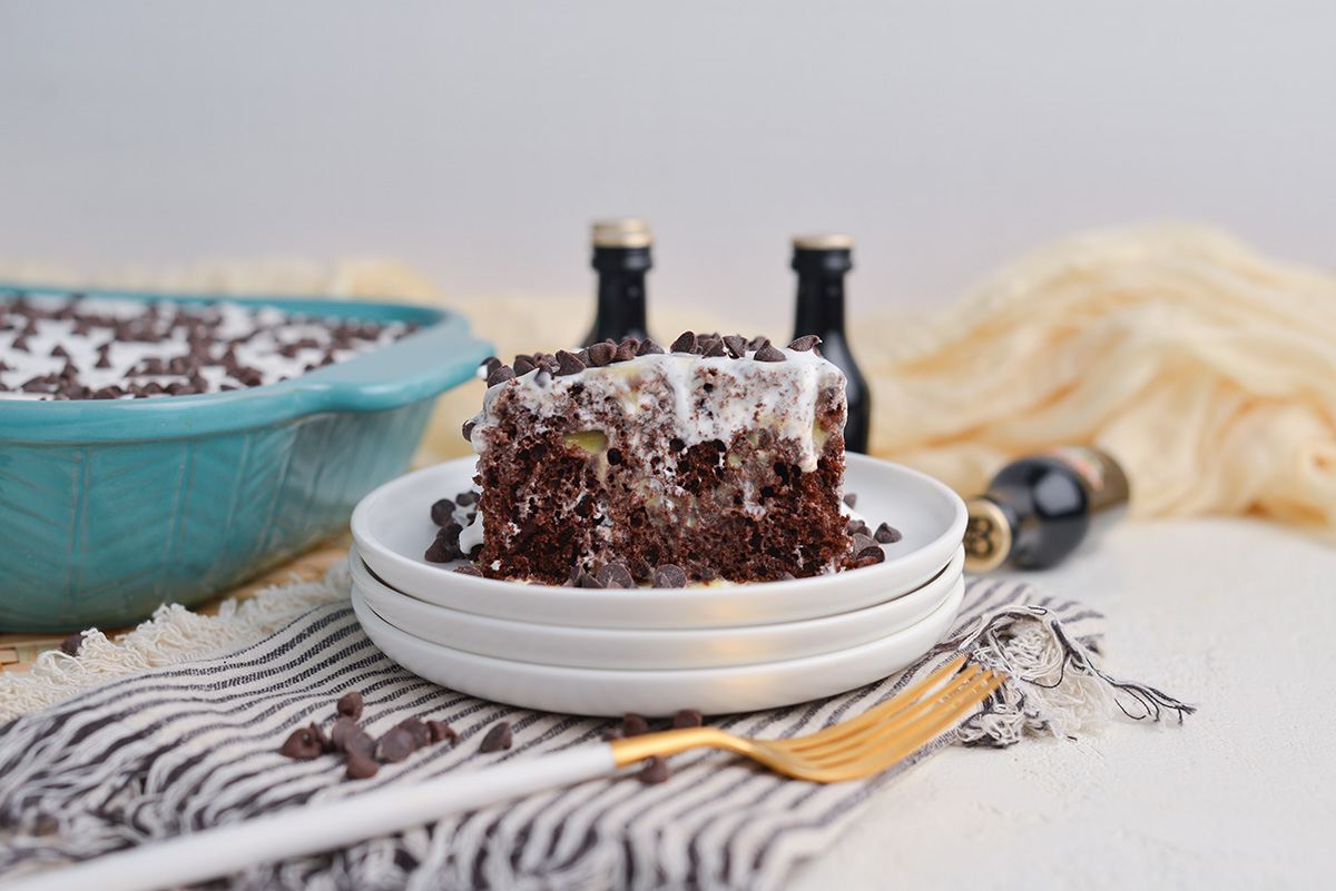 straight on shot of slice of irish cream poke cake on stack of plates