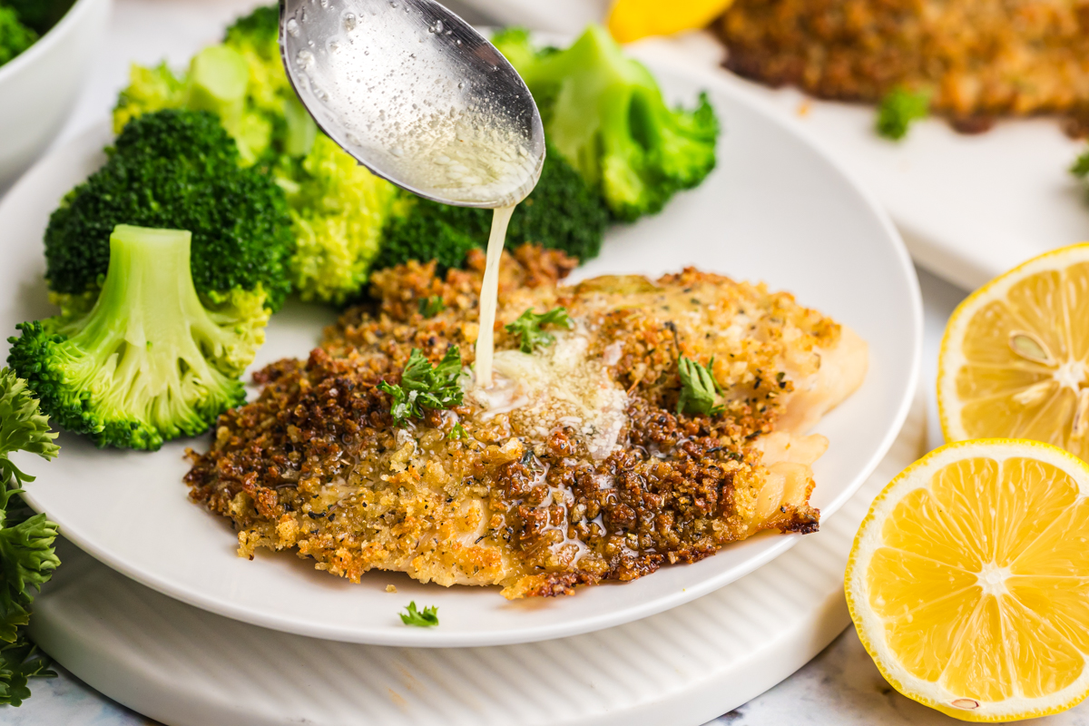 spoon adding melted butter to parmesan crusted tilapia