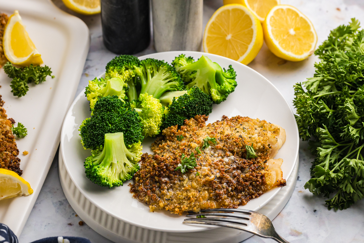 angled shot of plate of parmesan crusted tilapia with broccoli