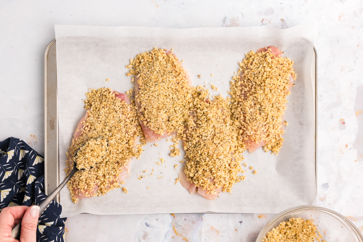 overhead shot of breading added to tilapia on sheet pan