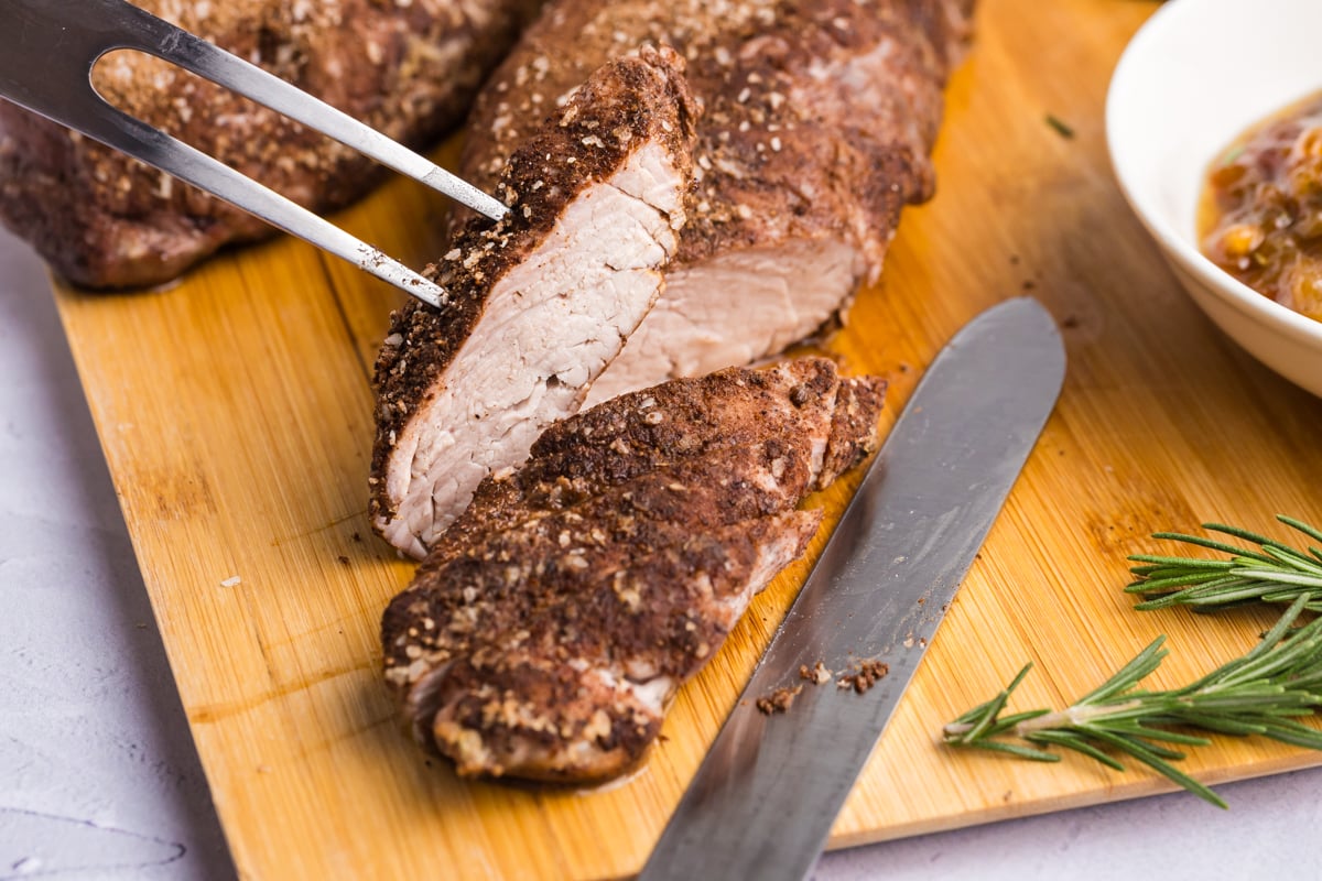 close up angled shot of sliced pork tenderloin on cutting board