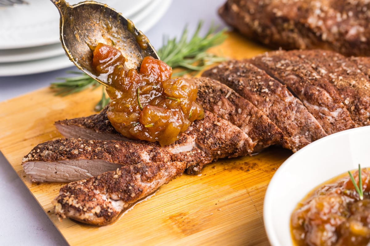 angled shot of date chutney spooned onto sliced pork tenderloin