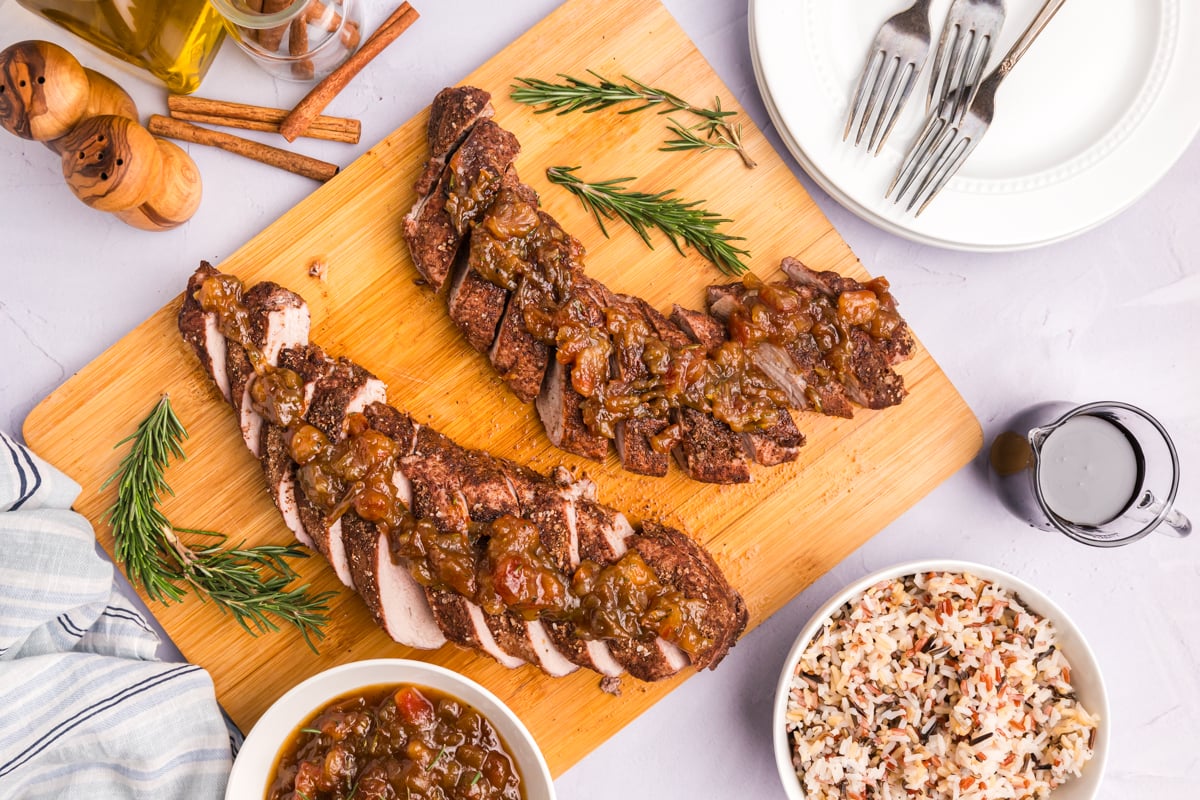 overhead shot of of two sliced pork tenderloins with date chutney on cutting board