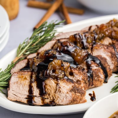 close up angled shot of sliced pork tenderloin on platter with rosemary