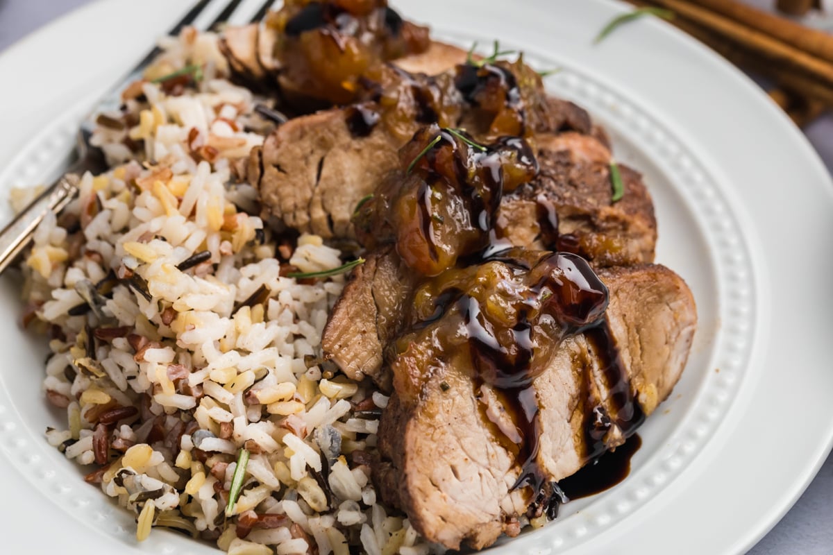 close up angled shot of sliced pork tenderloin with date chutney on plate with rice