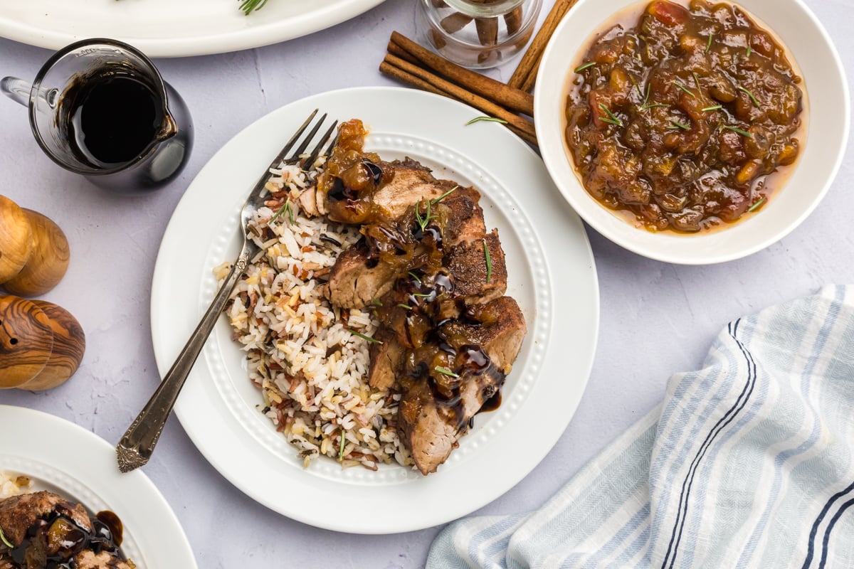 overhead shot of sliced pork tenderloin with date chutney on plate with rice