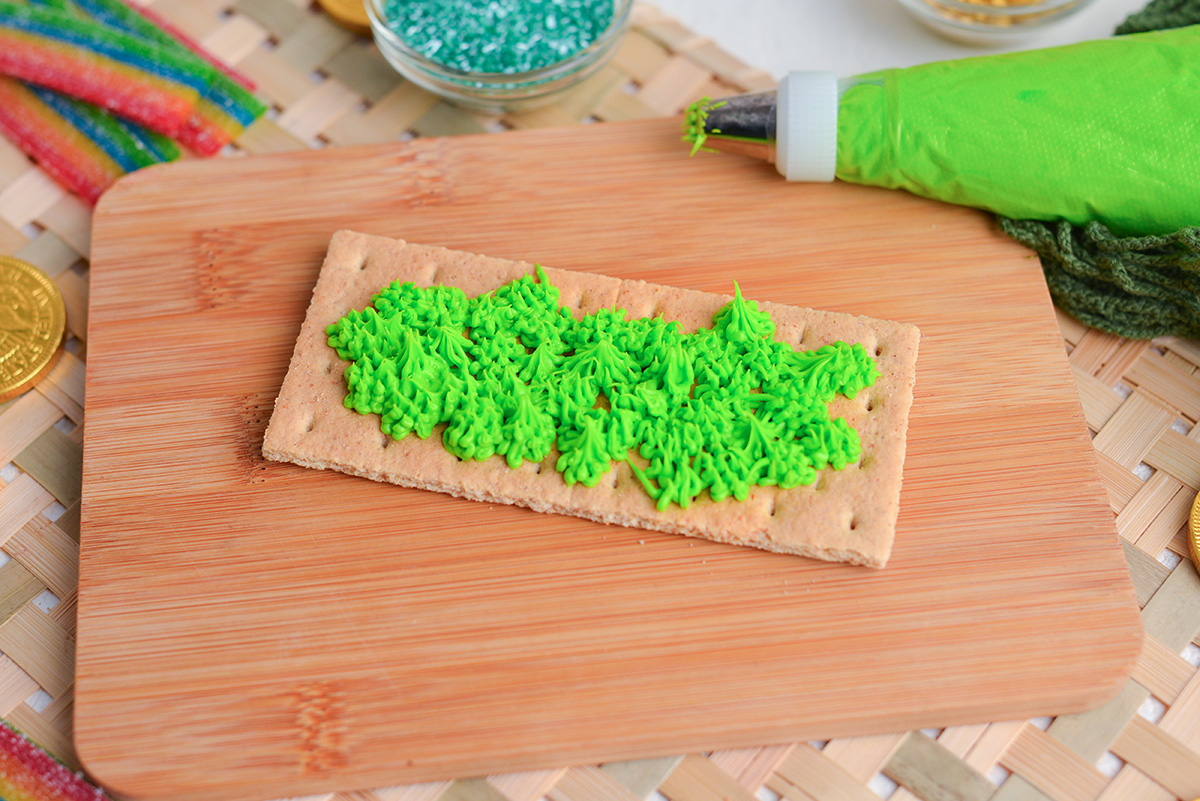 angled shot of green frosting piped onto graham cracker