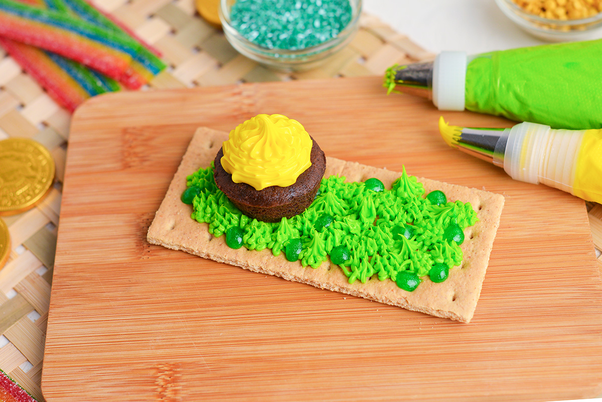 angled shot of pot of gold brownie placed on graham cracker with green grass icing