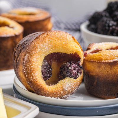 close up straight on shot of two blackberry popovers on a plate