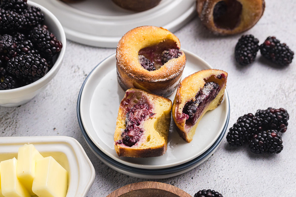 angled shot of blackberry popover cut in half on plate