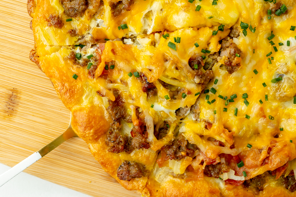 overhead shot of spatula under slice of breakfast pizza