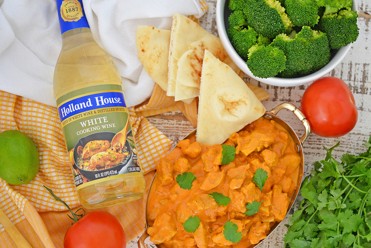 overhead shot of pita bread in bowl of indian butter chicken with white cooking wine