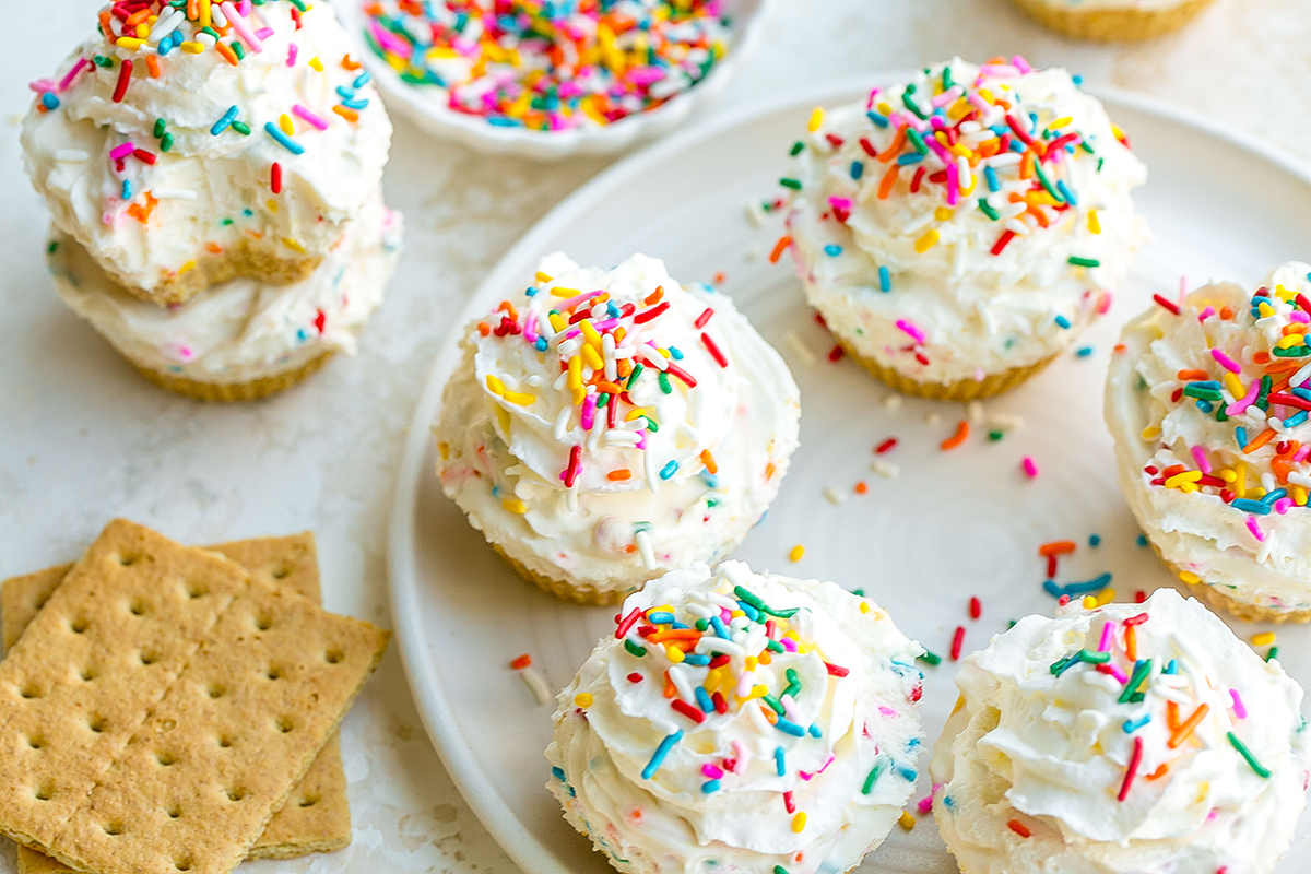 angled shot of plate of mini funfetti cheesecakes